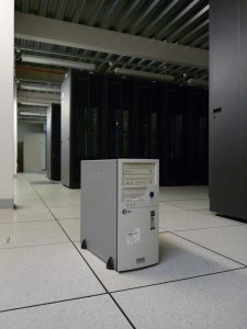 The single computer providing the Manchester grid site in 2001. In the background are the 40 racks of 1000 computers which had replaced it by 2005.